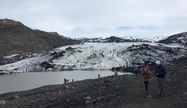 Tourists take pictures of the Solheimajokull glacier in southern Iceland, flowing from the Myrdalsjokull ice cap which covers the much feared Katla volcano, about 31 kilometers (19 miles) west of Vik, Iceland, March 29, 2017.  After a summer of increased seismic activity, seismologists keep watch for volcanic activity, and there's an alert system to warn all 543 residents in Vik if the volcano blows, but there is no system to alert tourists who are flocking to Iceland’s waterfalls and geysers in record numbers.(AP Photo /Sheila Norman-Culp)