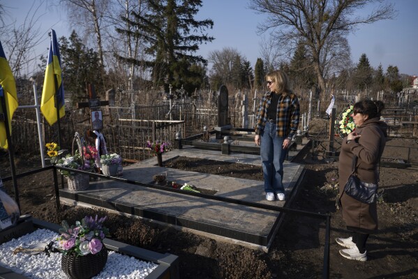 In Pyriatyn, Ukraine, Oksana Hryhorieva, left, and her mother, Halyna Hryhorieva, visit the grave of Serhii Hryhoriev, who died as a prisoner of war in Russia, March 9, 2025. (AP Photo/Alex Babenko)