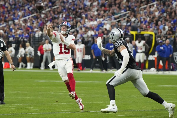 New York Giants quarterback Tommy DeVito (15) throws a touchdown pass as Las Vegas Raiders defensive end Maxx Crosby (98) defends during the second half of an NFL football game, Sunday, Nov. 5, 2023, in Las Vegas. (AP Photo/Rick Scuteri)