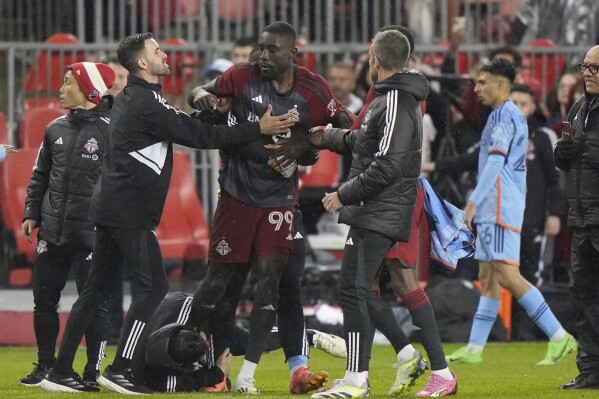 Toronto FC forward Prince Osei Owusu (99) is restrained by team staff members after the team's MLS soccer match against New York City FC on Saturday, May 11, 2024, in Toronto. (Frank Gunn/The Canadian Press via Ǻ)