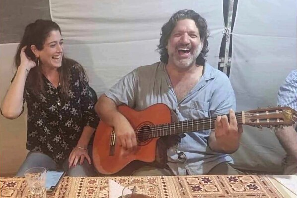 This image provided by Eran Shani shows Shlomi Mathias playing the guitar as his wife, Debbie ‘Shahar’ Mathias, laughs and sings next to him at her 50th birthday party on Oct. 1, 2023, in Lehavim, Israel. They both died days later while protecting their 16-year-old son, Rotem Mathias, from Hamas fighters who attacked their kibbutz in Israel near the border with Gaza on Oct. 7, 2023. (Eran Shani via AP)