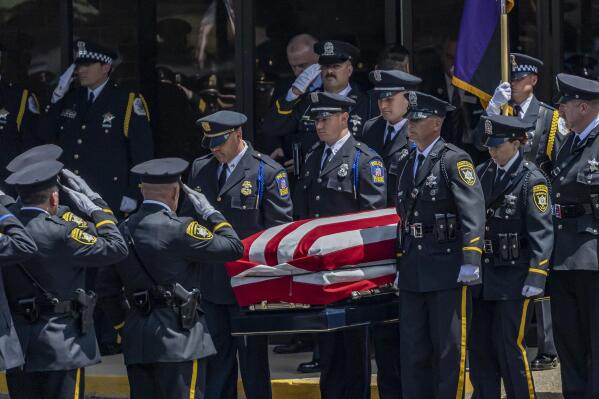 Police officers stand at attention as Champaign police Officer Chris Oberheim's casket is carried out of  Maranatha Assembly of God Church during a funeral service, Wednesday, May 26, 2021, in Decatur, Ill. Oberheim was killed early Wednesday, May 19, during a shootout at an apartment complex.  (Clay Jackson/Herald & Review via AP)
