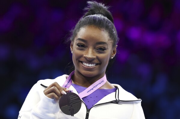 United States' Simone Biles shows her gold medal on the beam during the apparatus finals at the Artistic Gymnastics World Championships in Antwerp, Belgium, Sunday, Oct. 8, 2023. (AP Photo/Geert vanden Wijngaert)