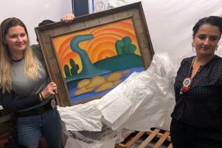 In this photo provided by the Rio de Janeiro Civil Police, officers show artist Tarsila do Amaral's painting titled "Sol Poente" after it was seized during a police operation in Rio de Janeiro, Brazil, Wednesday, Aug. 10, 2022. Police say they seek the arrest of six people accused of stealing 16 artworks, valued at a total of more than 700 million reais ($139 million), stolen from an 82-year-old widow whose daughter orchestrated the theft. (Rio de Janeiro Civil Police via AP)