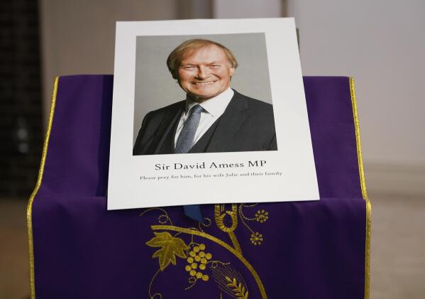 FILE - In this  Friday, Oct. 15, 2021 file photo, an image of murdered British Conservative lawmaker David Amess is displayed near the altar in St Peters Catholic Church before a vigil in Leigh-on-Sea, Essex, England. British authorities say a man has been charged with murder and preparing acts of terrorism in the stabbing of a Conservative lawmaker who was killed as he met constituents at a church hall last week Police say Ali Harbi Ali, a 25-year-old British man with Somali heritage, has been charged in the death of David Amess. (AP Photo/Alberto Pezzali, File)