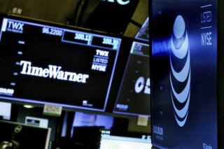 FILE - In this June 13, 2018, file photo, the logos for Time Warner and AT&T appear above alternate trading posts on the floor of the New York Stock Exchange. A federal appeals court has blessed AT&T's takeover of Time Warner, Tuesday, Feb. 26, 2019, defeating the Trump administration by affirming that the $81 billion merger won't harm consumers or competition in the booming pay TV market. (AP Photo/Richard Drew, File)