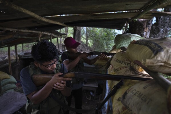 Zuan Vaiphei, 32, left, an armed tribal Kuki, keeps a watch on rival Meitei community bunkers, along a de facto frontline which dissect the area into two ethnic zones in Churachandpur, in the northeastern Indian state of Manipur, Tuesday, June 20, 2023. Two months ago, Vaiphei was teaching economics to students when the simmering tensions between the two communities exploded. The deadly clashes have left at least 120 dead by the authorities' conservative estimates. Other Kukis and Meiteis are asking questions they thought they would never ask: Should they also pick up arms and fight? (AP Photo/Altaf Qadri)