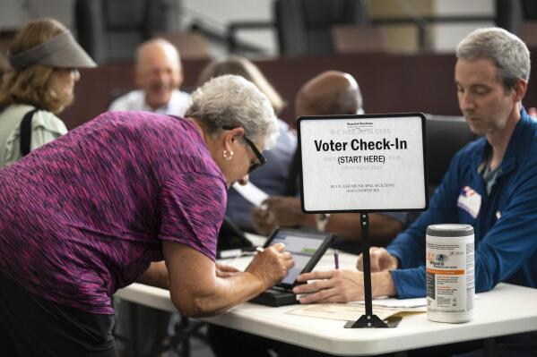 FILE - A poll worker prepares to give a ballot to a voter at the Blue Ash, Ohio Municipal building for the primary, Aug. 2, 2022. A bipartisan effort among states to combat voter fraud has found itself in the crosshairs of conspiracy theories fueled by Donald Trump’s false claims about the 2020 presidential election and now faces an uncertain future. (Liz Dufour/The Cincinnati Enquirer via AP, File)