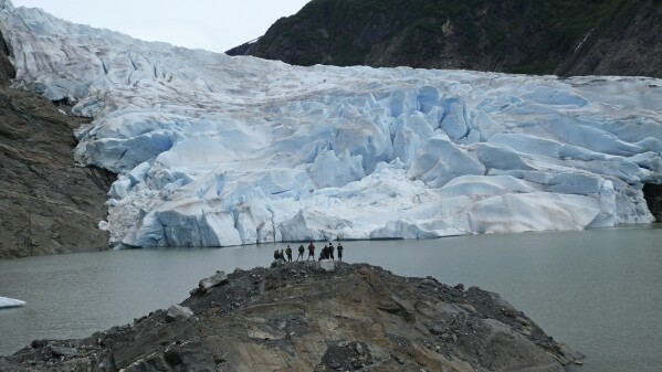 A group of people take in the views of the Mendenhall Glacier on June 8, 2023, in Juneau, Alaska. The glacier in the summer is accessible by kayak or canoe, by foot on a challenging trail or by helicopter. (AP Photo/Becky Bohrer)