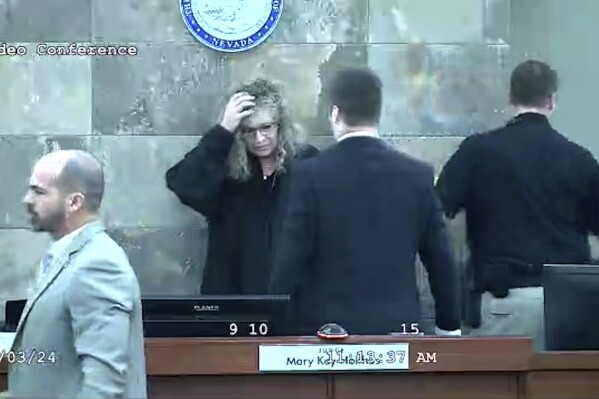 In this image from video provided by the Clark County District Court, Judge Mary Kay Holthus is seen cradling her head after a defendant launched over her desk during his sentencing in a felony battery case, Wednesday, Jan. 3, 2024 in Las Vegas. Redden, who was captured in courtroom video leaping over a judge's bench and attacking her, touching off a bloody brawl, is scheduled to appear before her again Monday morning, Jan. 8, 2024. (Clark County District Court via AP)