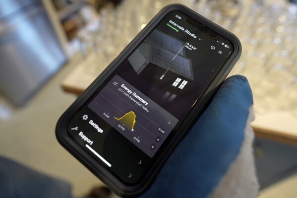 Farmer Hugh Lassen checks an app that shows the solar panel electricity production at Intervale Farm, Monday, Feb. 10, 2025, in Cherryfield, Maine. (AP Photo/Robert F. Bukaty)