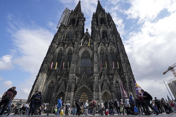 FILE - People line up in front of the Cologne Cathedral for free food at a nearby food bank in Cologne, Germany, Friday, Sept. 24, 2021. The archbishop of Cologne, one of Germany's most important Catholic dioceses, on Friday, Aug. 18, 2023 expressed disappointment that employees used work computers to try to access pornographic websites. (AP Photo/Martin Meissner, File)
