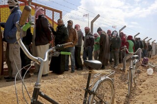 FILE - Syrian refugees line up to register their names at an employment office, Feb. 18, 2018, at the Azraq Refugee Camp, 100 kilometers (62 miles) east of Amman, Jordan. The United Nations food agency said Tuesday, July 18, 2023, that it will reduce monthly cash aid for 120,000 Syrian refugees living in camps in Jordan because of what it described as an “unprecedented funding crisis.” (AP Photo/Raad Adayleh, File)