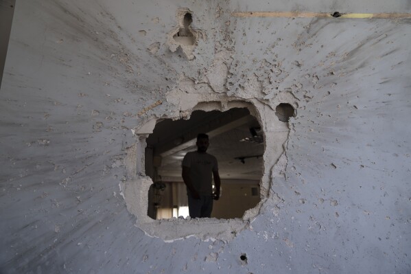 A Palestinian family member inspects the damage at his family's house that was besieged during an Israeli army raid in the West Bank town of Aqaba, near Tubas, Friday, Sept. 1, 2023. The Israeli military on Friday raided the Palestinian town in the northern West Bank, besieging an apartment and sparking a gunfight with local militants that killed an apparently uninvolved Palestinian teacher, his family and Palestinian health officials said. The Israeli army said it searched the hide-out and found improvised explosive devices in a children's room, along with other military equipment like high-capacity gun magazines. (AP Photo/Nasser Nasser)