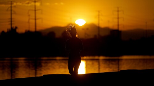 Una deportista corre al lado del lago Tempe Town al amanecer del miércoles 12 de julio de 2023, en Tempe, Arizona. (AP Foto/Matt York)