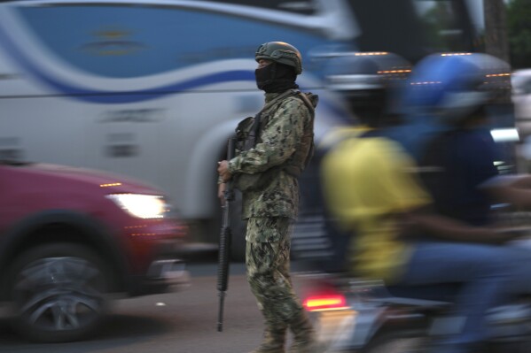 FILE - A soldier monitors vehicle traffic on the National Unity Bridge that connects the town of Duran with the Guayaquil, Ecuador, July 20, 2023. Guayaquil is the epicenter of violence. About a third of this year’s violent deaths took place in what is Ecuador’s second-largest city and home to the main commercial port, as well as a large prison complex. (AP Photo/Dolores Ochoa, File)