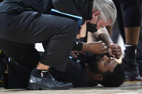 Miami Heat forward Markieff Morris, bottom, is attended to after being in an altercation with Denver Nuggets center Nikola Jokic in the second half of an NBA basketball game Monday, Nov. 8, 2021, in Denver. Morris walked off the court after being examined and Jokic was ejected. (AP Photo/David Zalubowski)