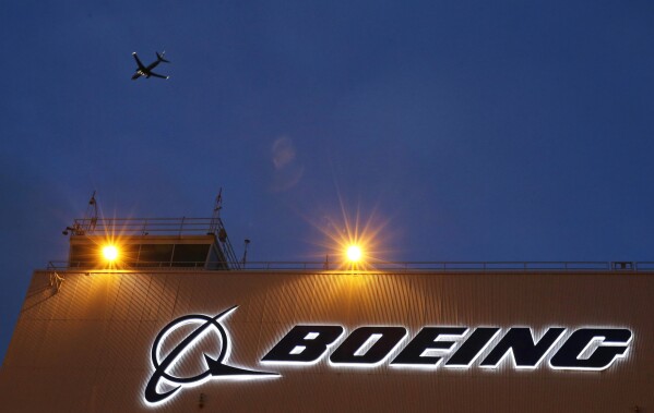 FILE - An airplane flies over a sign on Boeing's 737 delivery center, Oct. 19, 2015, at Boeing Field in Seattle. The Justice Department's determination on Tuesday, May 14, 2024, that Boeing violated corporate probation for deceiving federal regulators does not necessarily mean that prosecutors will revive criminal charges against the giant aircraft manufacturer. (AP Photo/Ted S. Warren, File)