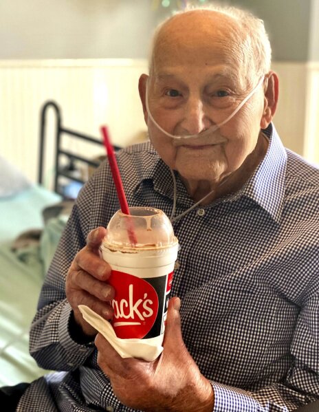 In this photo provided by Holly Wooten McDonald, World War II veteran and COVID-19 survivor Major Wooten holds a celebratory milkshake on his 104th birthday on Thursday, Dec. 3, 2020, in Madison, Alabama. Wooten was released from the hospital this week after contracting the illness caused by the new coronavirus before Thanksgiving. (Holly Wooten McDonald via AP)