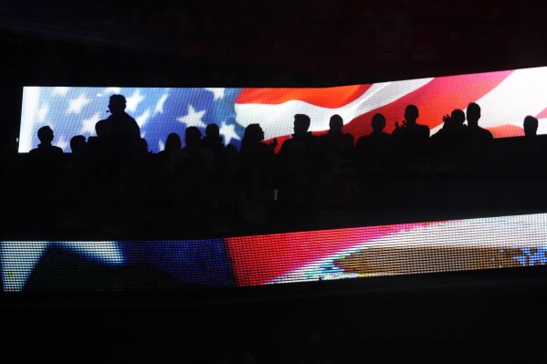 Fans at United Center stand for the national anthem before an NHL hockey game between the Vancouver Canucks and the Chicago Blackhawks in Chicago, Sunday, Dec. 17, 2023. (AP Photo/Nam Y. Huh)