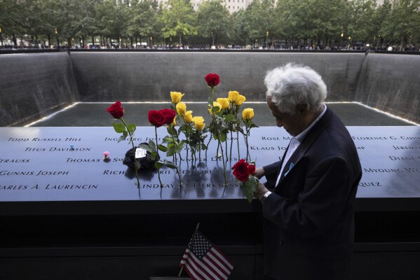 Hagi Abucar puts flowers on the 9/11 Memorial during the commemoration ceremony on the 22nd anniversary of the September 11, 2001, terror attacks on Monday, Sept. 11, 2023, in New York. (AP Photo/Yuki Iwamura)
