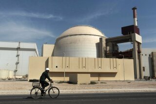 FILE - In this Oct. 26, 2010 file photograph, a worker rides a bicycle in front of the reactor building of the Bushehr nuclear power plant, just outside the southern city of Bushehr. Iran's deputy foreign minister said Thursday, Jan 31, 2019, that he believes European Union nations soon will announce they've created a program for Iran to continue trade there and avoid re-imposed U.S. sanctions over its nuclear program. (AP Photo/Mehr News Agency, Majid Asgaripour, File)