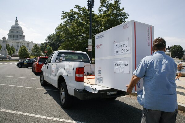 Paul Falcon unloads a custom made "Priority Mail" box that organizers said contained two million signed petitions from postal customers asking Congress to approve emergency funding for the Postal Service, Tuesday, June 23, 2020, on Capitol Hill in Washington. Postal Service employees and supporters are urging Congress to to invest $25 billion to help the public Postal Service "weather the pandemic and the deep recession." (AP Photo/Jacquelyn Martin)
