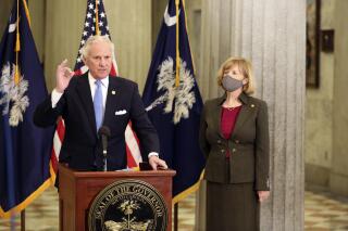 FILE - In this Thursday, Feb. 4, 2021, file photo, South Carolina Gov. Henry McMaster, left, and state Education Superintendent Molly Spearman, right, talk about a Senate proposal to get teachers COVID-19 vaccines immediately, in Columbia, S.C. A budget proviso that went into effect July 1 prohibits school districts in South Carolina from using appropriated funds “to require that its students and/or employees wear a face mask at any of its education facilities.” The measure was backed by Gov. McMaster. (AP Photo/Jeffrey Collins, File)