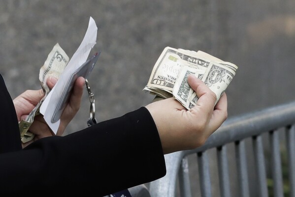 2017年9月26日，一名女性在纽约街头小贩那里购物时用现金付款。尽管数据显示整体经济状况良好，但低收入人群仍表现出压力。（美联社照片/马克·伦尼汉）