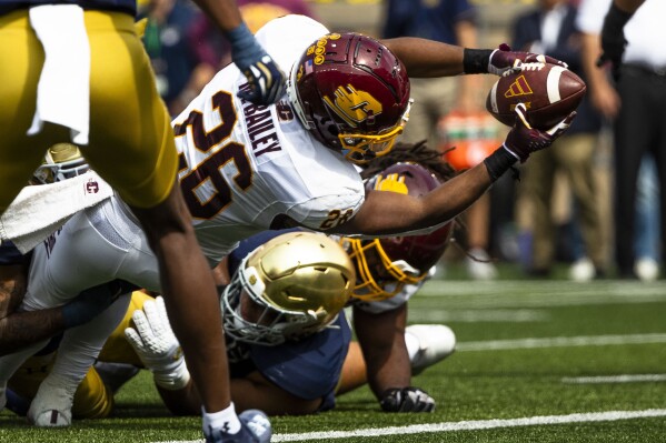 Central Michigan's Myles Bailey (26) reaches over Notre Dame's Howard Cross III (56) to score during the first half of an NCAA college football game on Saturday, Sept. 16, 2023, in South Bend, Ind. (AP Photo/Michael Caterina)