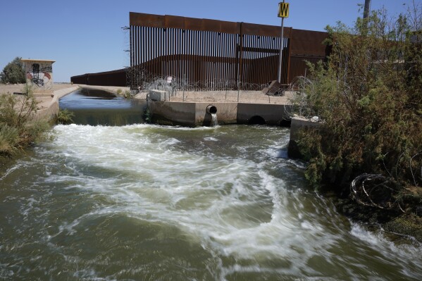 FILE - Water from the Colorado River flows in a canal along a border wall separating San Luis Rio Colorado, Mexico from San Luis, Arizona on Aug. 14, 2022, in San Luis Rio Colorado, Mexico. Among the last cities downstream to receive water from the shrinking Colorado River, Tijuana is staring down a water crisis. (AP Photo/Gregory Bull, File)