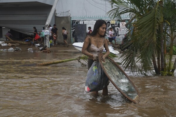 A woman walks carries a mirror looted from a furniture store after Hurricane Otis ripped through Acapulco, Mexico, Wednesday, Oct. 25, 2023. Hurricane Otis ripped through Mexico's southern Pacific coast as a powerful Category 5 storm, unleashing massive flooding, ravaging roads and leaving large swaths of the southwestern state of Guerrero without power or cellphone service. (AP Photo/Marco Ugarte)