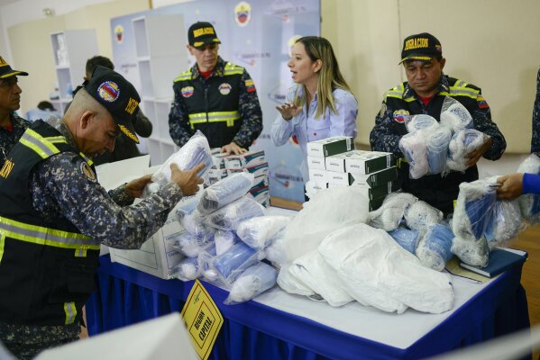 Members of Bolivarian Immigration National Police unpack biosafety supplies that include infrared thermometers, protective masks and gloves, part of preparations to help prevent the spread of the new coronavirus, at the National Experimental Security University in Caracas, Venezuela, Friday, March 13, 2020. For most people, the new coronavirus causes only mild or moderate symptoms, such as fever and cough. For some, especially older adults and people with existing health problems, it can cause more severe illness, including pneumonia.  (AP Photo/Matias Delacroix)