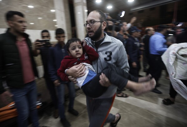 A wounded Palestinian child is carried into the Nasser Hospital following an Israeli bombardment on Khan Younis refugee camp, southern Gaza Strip, Tuesday, Nov. 21, 2023. (AP Photo/Mohammed Dahman)