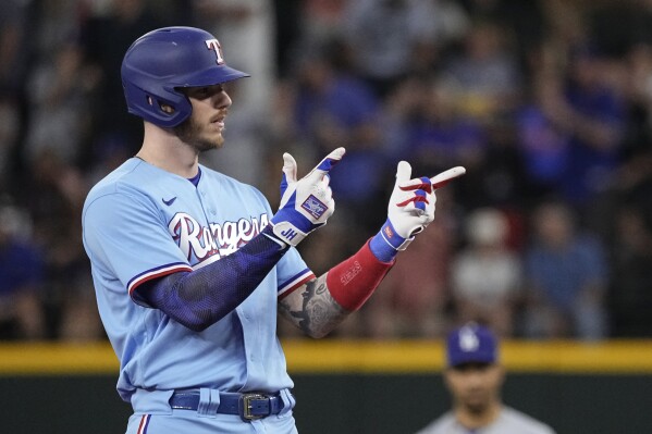 Texas Rangers' Jonah Heim gestures to his dugout after hitting a two-RBI double against the Los Angeles Dodgers during the first inning of a baseball game, Sunday, July 23, 2023, in Arlington, Texas. (AP Photo/Sam Hodde)