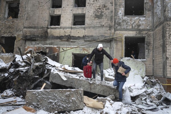 FILE - People walk with belongings out from an apartment building destroyed after Tuesday's Russian attack in Kyiv, Ukraine, Jan. 3, 2024. House Democrats on Tuesday, March 12, 2024, launched a long-shot effort to push $95 billion in aid for Ukraine, Israel and Taiwan to a vote. The move ramps up pressure on House Speaker Mike Johnson to take up the foreign funding package. (AP Photo/Efrem Lukatsky, File)