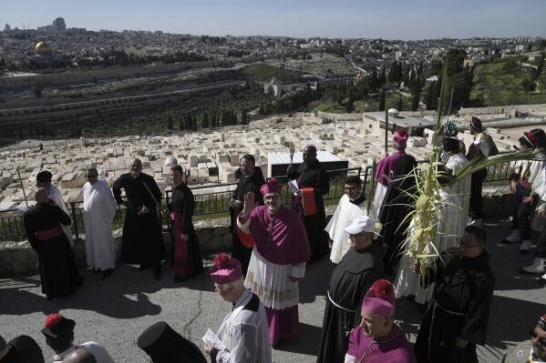 Pierbattista Pizzaballa, the Latin Patriarch of Jerusalem, center, waves during the Palm Sunday procession on the Mount of Olives in east Jerusalem, Sunday, April 2, 2023. The procession observes Jesus' entrance into Jerusalem in the time leading up to his crucifixion, which Christians mark on Good Friday. (AP Photo/Mahmoud Illean)