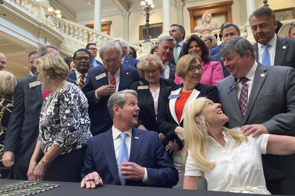 Georgia Gov. Brian Kemp, bottom center, speaks to state Sen. Larry Walker III, R-Perry, right, before signing bills into law at the state Capitol on Tuesday, May 2, 2023, in Atlanta. Georgia's state government will for the first time run its own marketplace for individual health insurance under a law that Republican Gov. Kemp signed. (AP Photo/Jeff Amy)