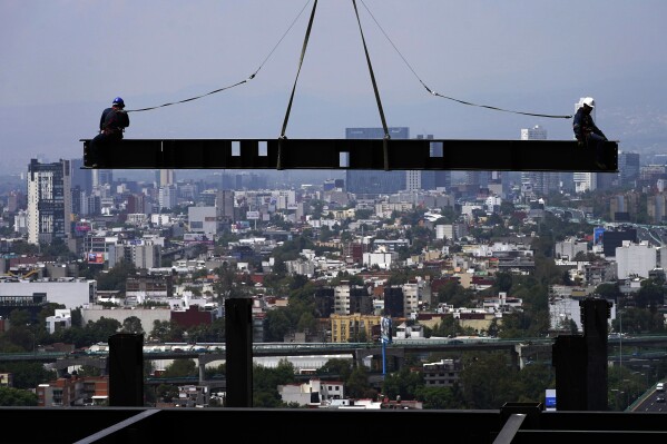 FILE - Construction workers sit on a beam hanging from a crane at a construction site of a residential high rise building, in Mexico City, June 17, 2022. Mexico鈥檚 president said Friday, Dec. 1, 2023, the country鈥檚 minimum wage will rise by 20% in 2024, to the equivalent of about $14.25 per day. (AP Photo/Marco Ugarte, File)