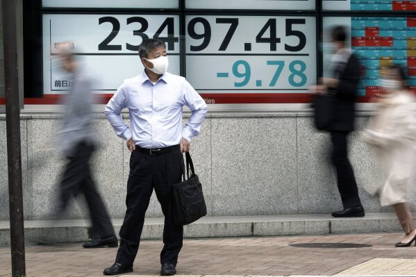 A man stands near an electronic stock board showing Japan's Nikkei 225 index at a securities firm in Tokyo Friday, Oct. 16, 2020. Asian shares were mixed on Friday as investors weighed concerns about the U.S. presidential election and an economic stimulus package, on top of fears of flaring outbreaks of coronavirus. (AP Photo/Eugene Hoshiko)