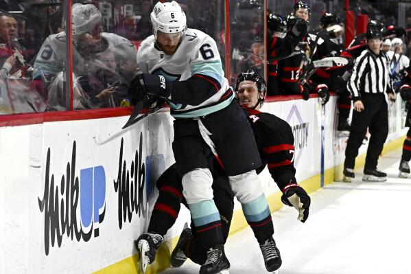 Seattle Kraken defenseman Adam Larsson (6) crashes into Ottawa Senators defenseman Thomas Chabot along the boards, leading to an interference penalty against the Kraken, during second-period NHL hockey game action in Ottawa, Ontario, Saturday, Jan. 7, 2023. (Justin Tang/The Canadian Press via AP)