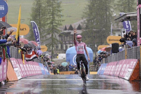 Slovenia's Tadej Pogacar, wearing the pink jersey of the race overall leader, indicates five, the numbers of Giro' stages he has won so far, as he crosses the finish line to win the 16th stage of the Giro d'Italia cycling race, from Livigno to Santa Cristina Val Gardena (Monte Pana), Italy, Tuesday, May 21, 2024. (Marco Alpozzi/LaPresse via AP)