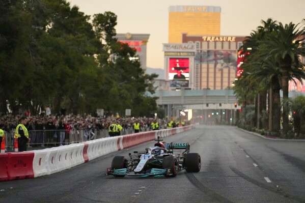 FILE - George Russell drives during a demonstration along the Las Vegas Strip at a launch party for the Formula One Las Vegas Grand Prix on Nov. 5, 2022. As the sport grows in popularity, race weekends are transforming into mini music festivals with A-list talent performing after the day's event. (AP Photo/John Locher, File)