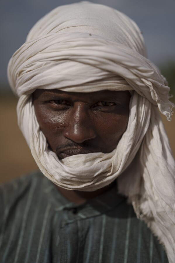 Moussa Ifra Ba, stands for a portrait in the village of Dendoudy Dow, in the Matam region of Senegal, Monday, April 17, 2023. The 28-year-old herder can't imagine any other life. "A village without cows has no soul. ... I love pastoralism to the core". The father of a two-year-old girl, he travels with his wife and her family taking care of the sheep and cows. "If I'm lucky enough to have three boys, I'd like two of them to go to school and the third to take over from me", he says. (AP Photo/Leo Correa)
