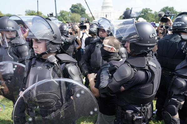 Police circle a man, center with glasses, during a rally near the U.S. Capitol in Washington, Saturday, Sept. 18, 2021. The rally was planned by allies of former President Donald Trump and aimed at supporting the so-called "political prisoners" of the Jan. 6 insurrection at the U.S. Capitol. (AP Photo/Gemunu Amarasinghe)