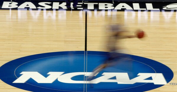 FILE - In this March 14, 2012, file photo, a player runs across the NCAA logo during practice in Pittsburgh. Widespread testing for the new coronavirus will be crucial to having college sports in the fall, especially contact sports such as football and basketball, the NCAA's chief medical officer said, Friday, May 1, 2020. (AP Photo/Keith Srakocic, File)