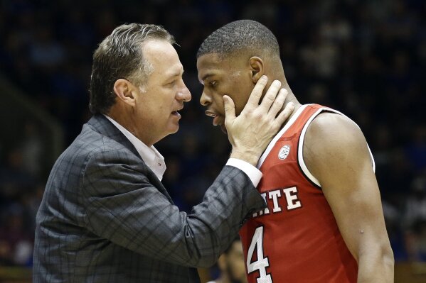 FILE - In this Jan. 23, 2017, file photo, N.C. State's head coach Mark Gottfried speaks with Dennis Smith Jr. during the second half of an NCAA college basketball game in Durham, N.C. North Carolina State’s NCAA case involving recruiting violations tied to former Wolfpack one-and-done star Smith Jr. has been recommended to go through an independent investigation process created for complex cases. Gottfried is charged individually in N.C. State's infractions case under the provision of head-coach responsibility for violations within his program. (AP Photo/Gerry Broome, File)