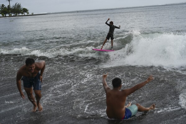 Kids surf small waves along the beach after school in Teahupo'o, Tahiti, French Polynesia, Monday, Jan. 15, 2024. (Ǻ Photo/Daniel Cole)