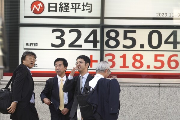 Business men gather in front of an electronic stock board showing Japan's Nikkei 225 index at a securities firm Thursday, Nov. 9, 2023, in Tokyo. Shares have fallen in Asia after a another mixed close as Wall Street recalibrates following recent big swings. (AP Photo/Eugene Hoshiko)