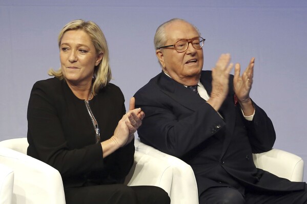 FILE - In this Saturday Nov. 29, 2014 file photo, French far-right Front National leader Marine Le Pen and her father Jean-Marie Le Pen applaud in Lyon, central France. A march against antisemitism this weekend in Paris, with the prime minister, government members, political parties and citizens in attendance, is fraught with discord over the planned presence of far-right leader Marine Le Pen. Her father and party founder Jean-Marie Le Pen has been convicted numerous times of antisemitism and racism. (AP Photo/Laurent Cipriani, File)